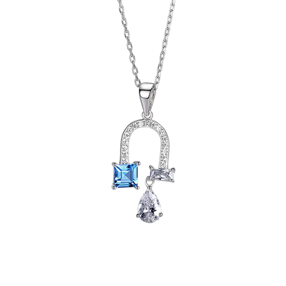 A silver pendant necklace featuring a small square blue gemstone and a teardrop-shaped clear gemstone, set on a delicate silver chain 