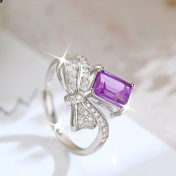Silver ring with a purple gemstone on a light background