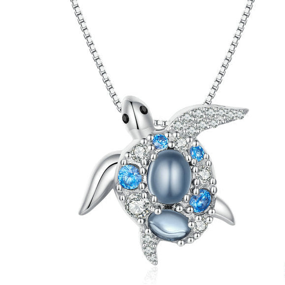 Silver turtle pendant with blue gemstones on a white background