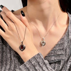 Two necklaces with pendants being held by a hand, one red and one silver.