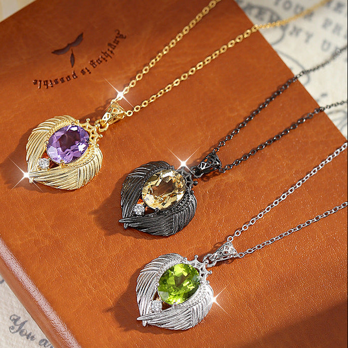 Three necklaces with leaf-shaped pendants on a brown book