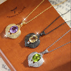 Three necklaces with leaf-shaped pendants on a brown book