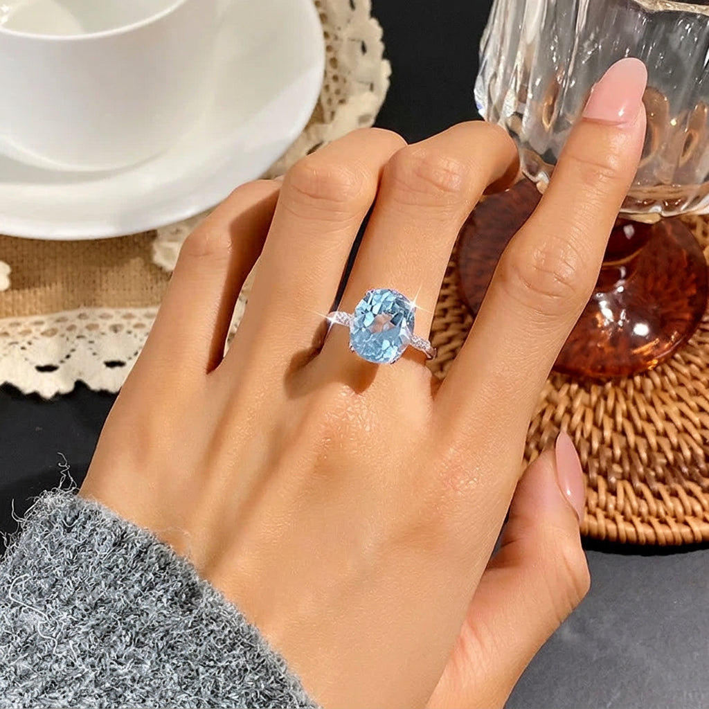 Hand wearing a blue gemstone ring with a blurred background