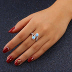 Hand wearing a silver ring with blue gemstones on a dark background