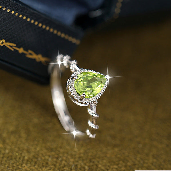 Silver ring with a green gemstone on a textured surface