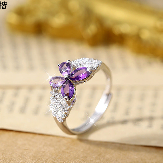Silver ring with purple gemstone on a textured surface