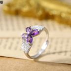 Silver ring with purple gemstone on a textured surface