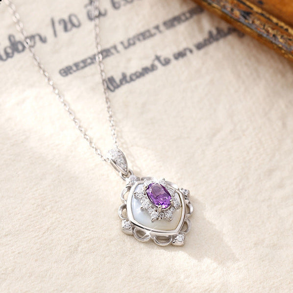 Silver necklace with a purple gemstone pendant on a textured surface