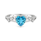 A silver-toned ring shown from multiple angles on a white background. The ring features a heart-shaped light blue gemstone in the center, small clear accent stones, and a split shank with tiny stones.