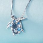 Tortoise-shaped pendant necklace with blue gemstones on a light blue background