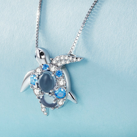 Tortoise-shaped pendant necklace with blue gemstones on a light blue background