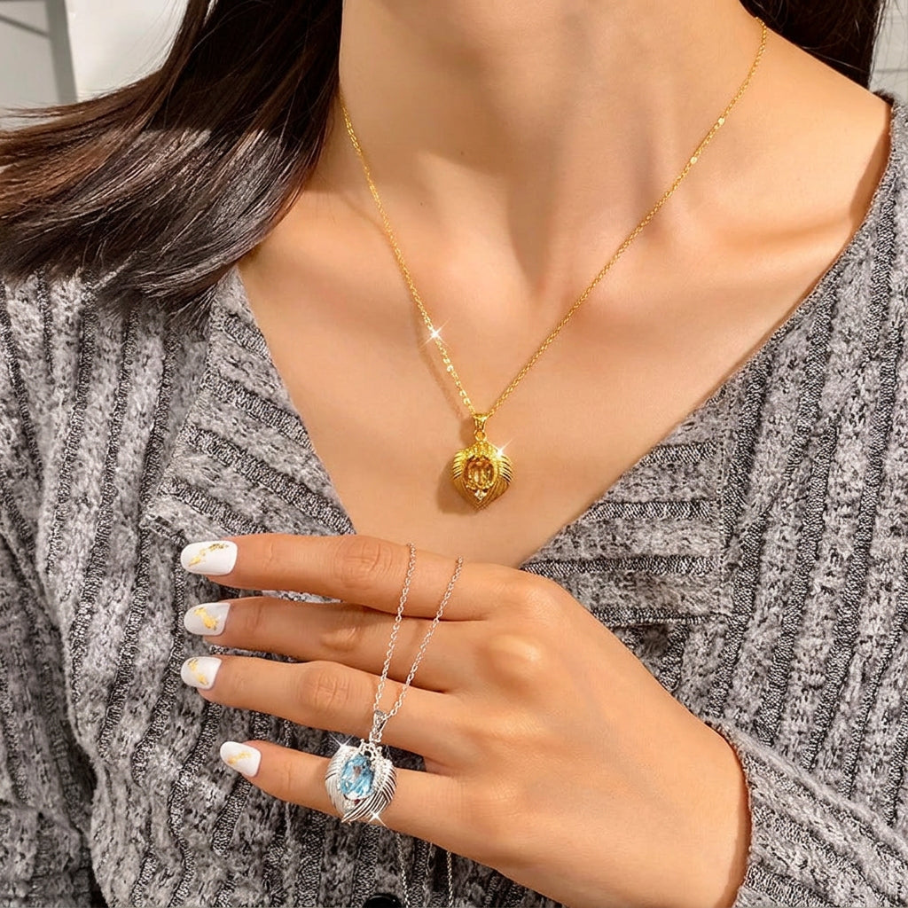 Person wearing a gold necklace with a pendant, holding a silver necklace with a blue gemstone pendant.