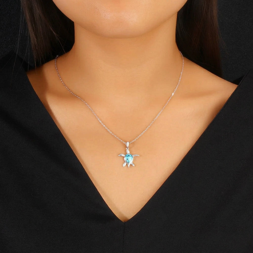 Necklace with a blue pendant worn by a person against a black background