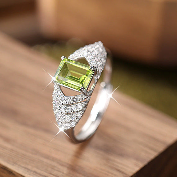 Silver ring with a green gemstone on a wooden surface