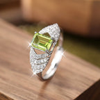 Silver ring with a green gemstone on a wooden surface