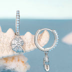 Silver earrings with a starfish charm on a coral background