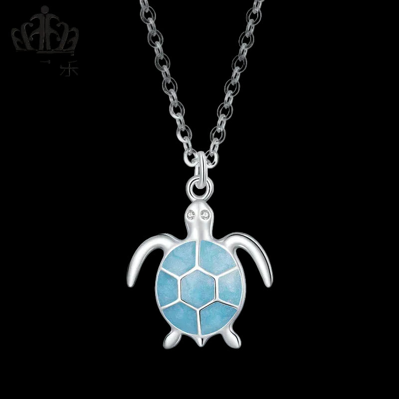 Silver turtle pendant necklace with blue accents on a white background