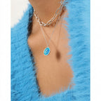 Necklace with a blue pendant worn by a person against a blue fur background
