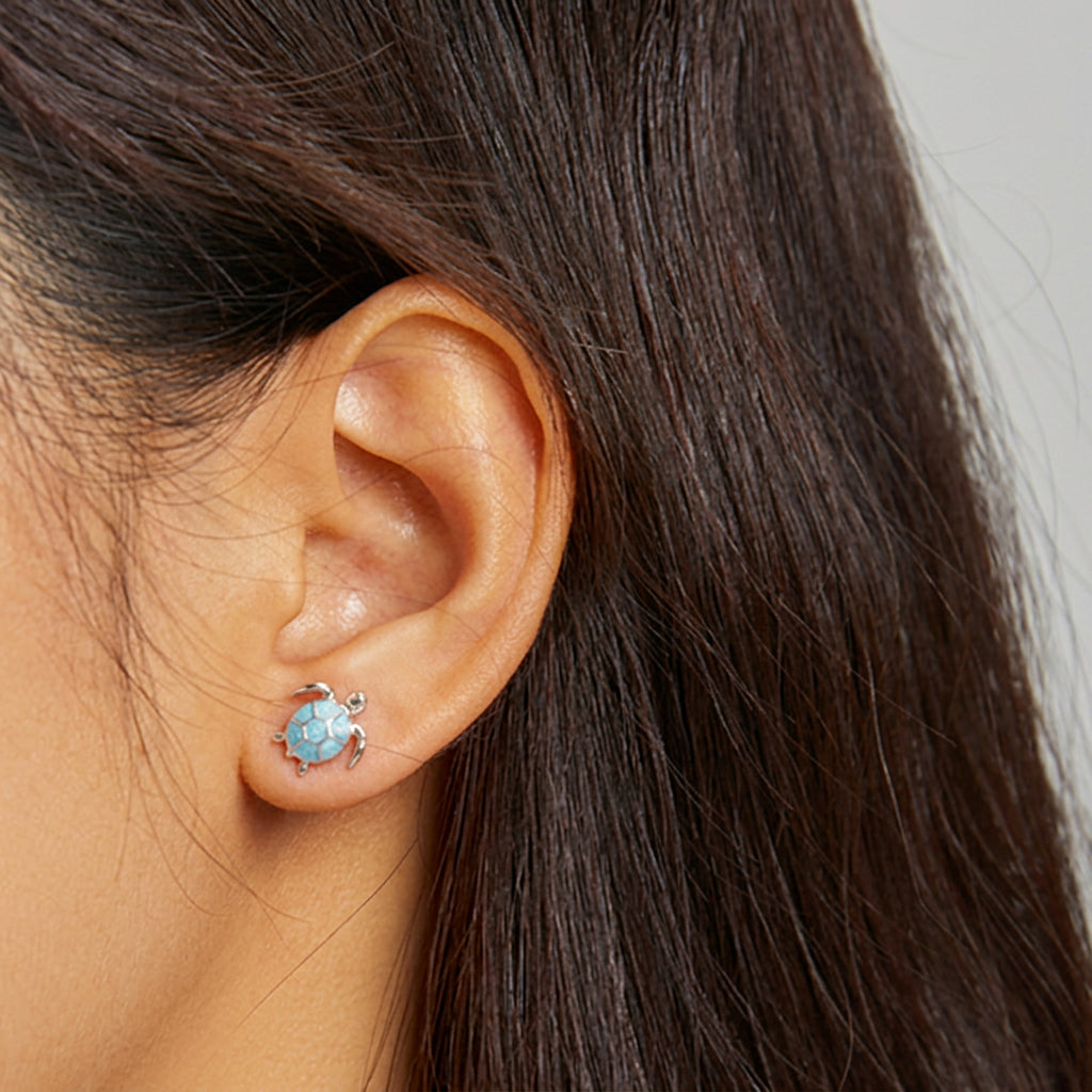 Close-up of a woman wearing a blue gemstone earring with a neutral background