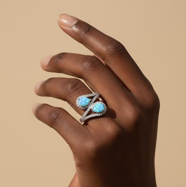 Hand wearing a ring with turquoise stones against a beige background