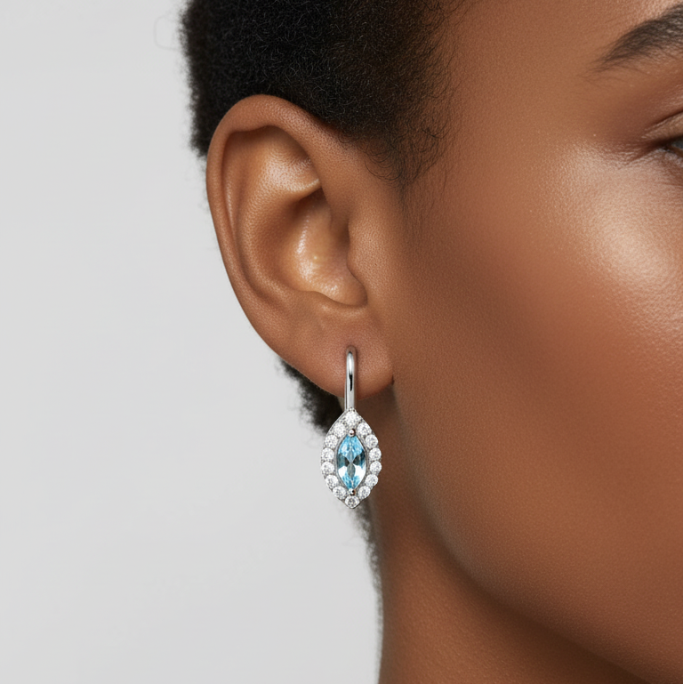 Close-up of a woman wearing a blue gemstone earring against a neutral background